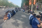 坐成一排，迟到的巴黎球迷用手机在香榭丽舍大道观赛